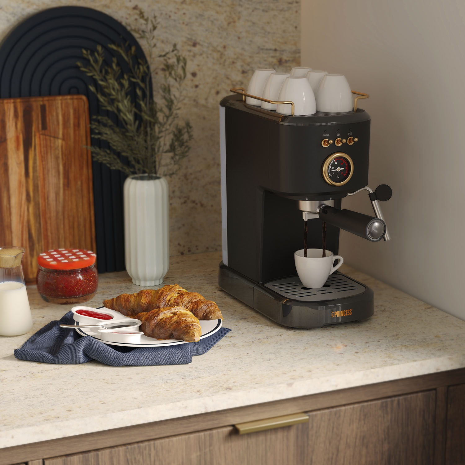Macchina per caffè che prepara l'espresso con croissant e marmellata sul tavolo.