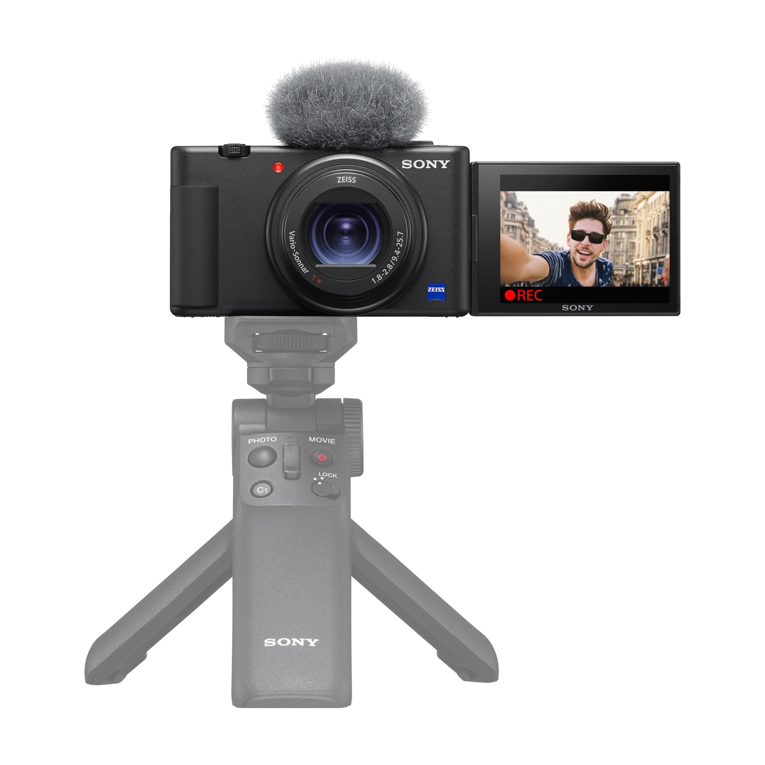 Fotocamera nera con microfono e schermo che mostra un uomo che registra. Montata su treppiede.