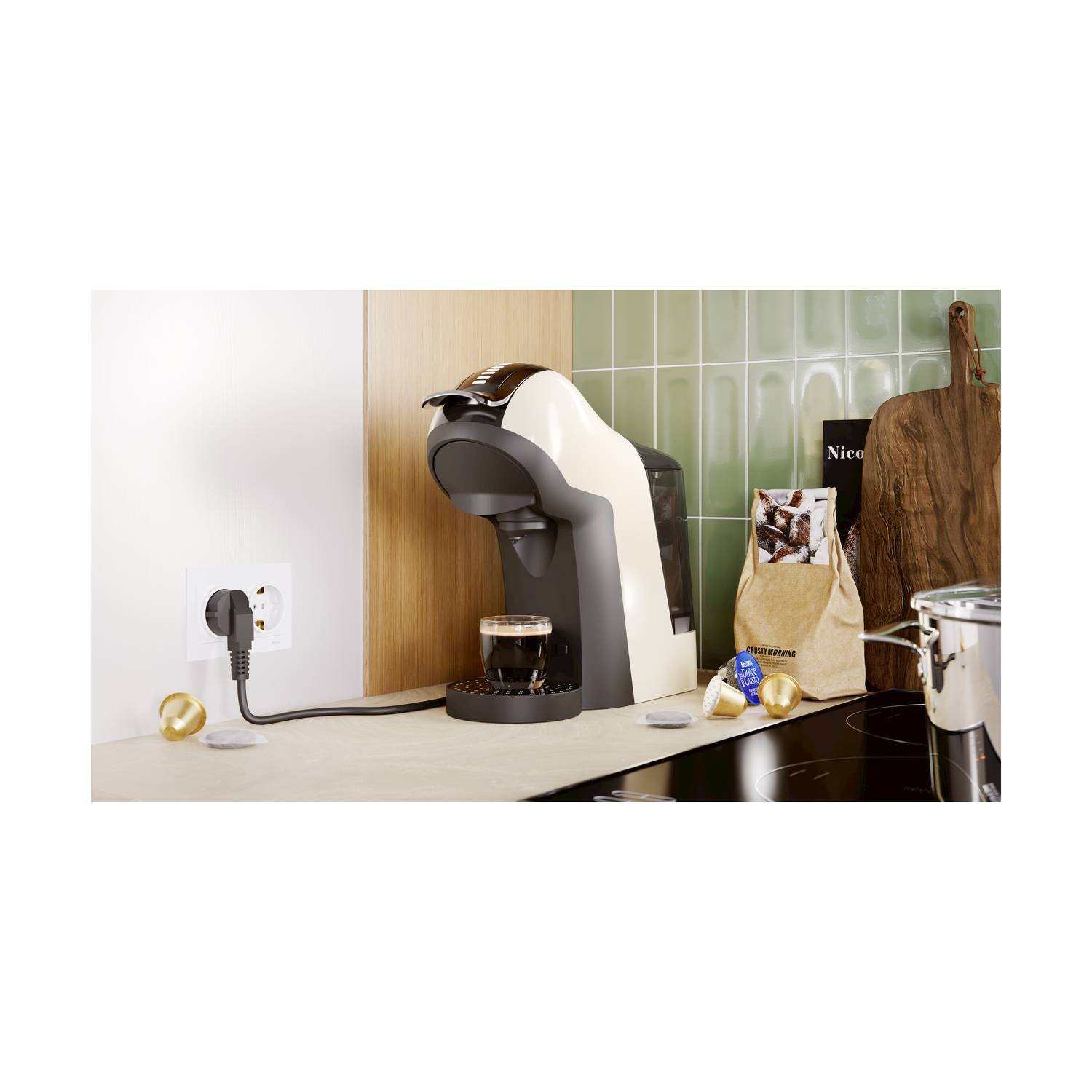 Caffettiera collegata, con caffè in preparazione. Cialde, un sacchetto e una spina sono sul bancone. Cucina.