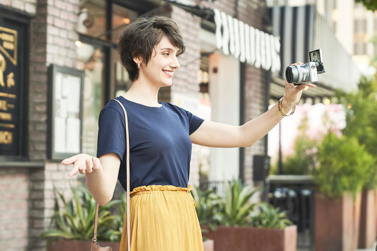 Frau macht ein Selfie mit einer Kamera auf einer Stadtstraße.