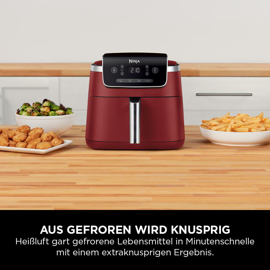 Roter Ninja Airfryer auf Holzoberfläche, mit Essen drumherum.