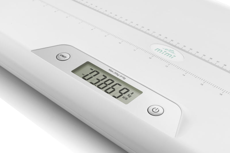 Egy fehér babamérleg digitális kijelzővel, amely 0,3869 kg súlyt mutat.