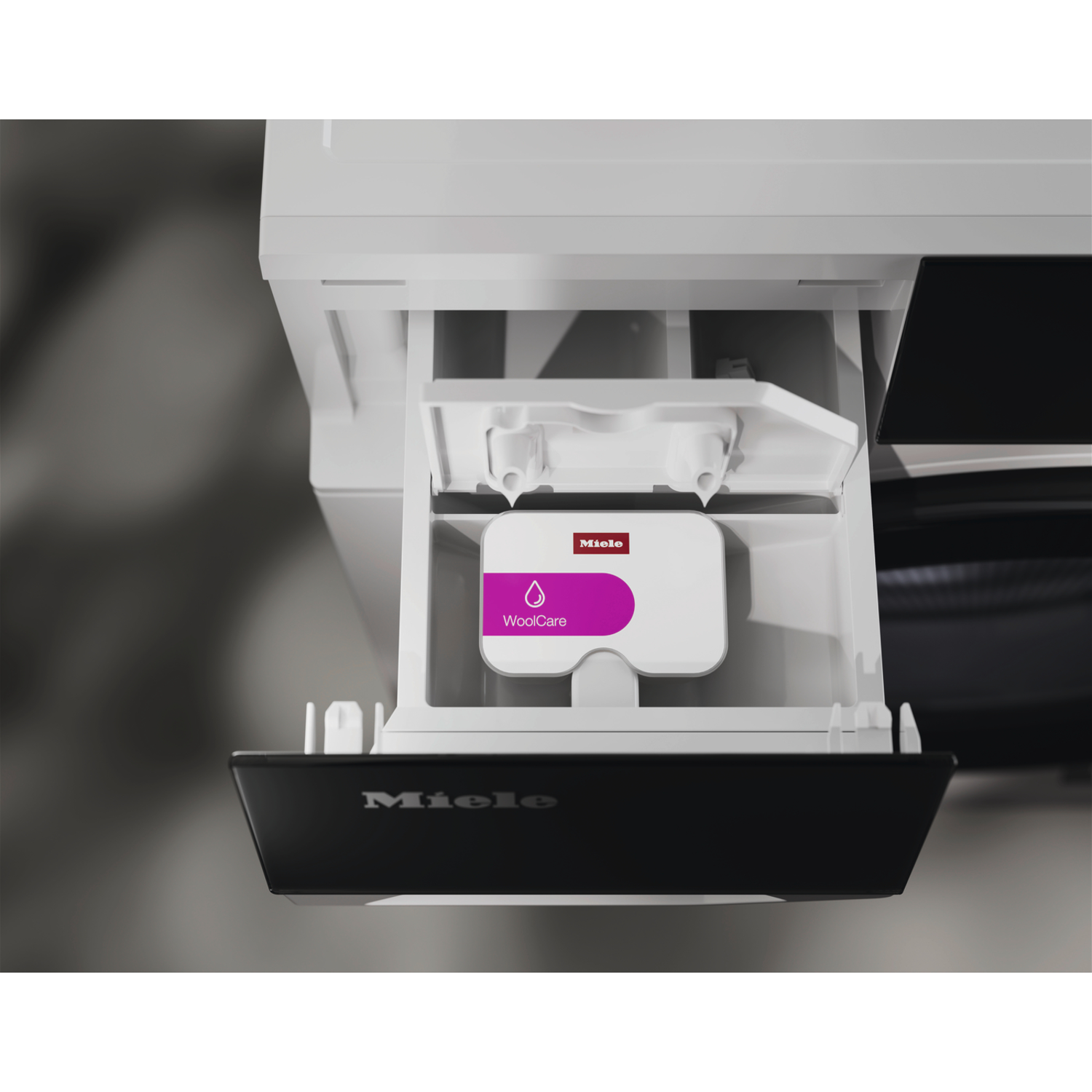 Laundry detergent drawer with a WoolCare detergent pod. White and black washing machine.
