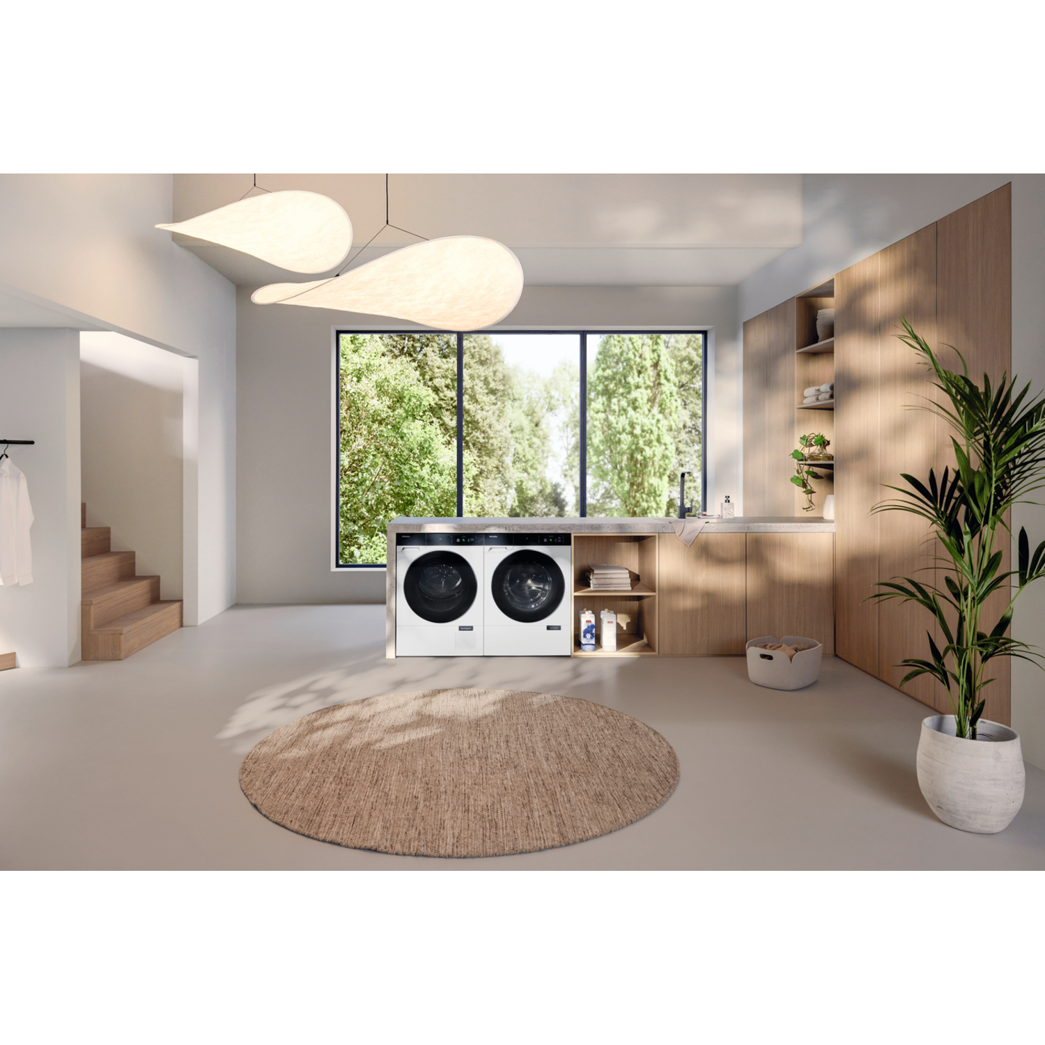 Laundry room with white washer/dryer, rug, and plants. Large windows and wooden accents.