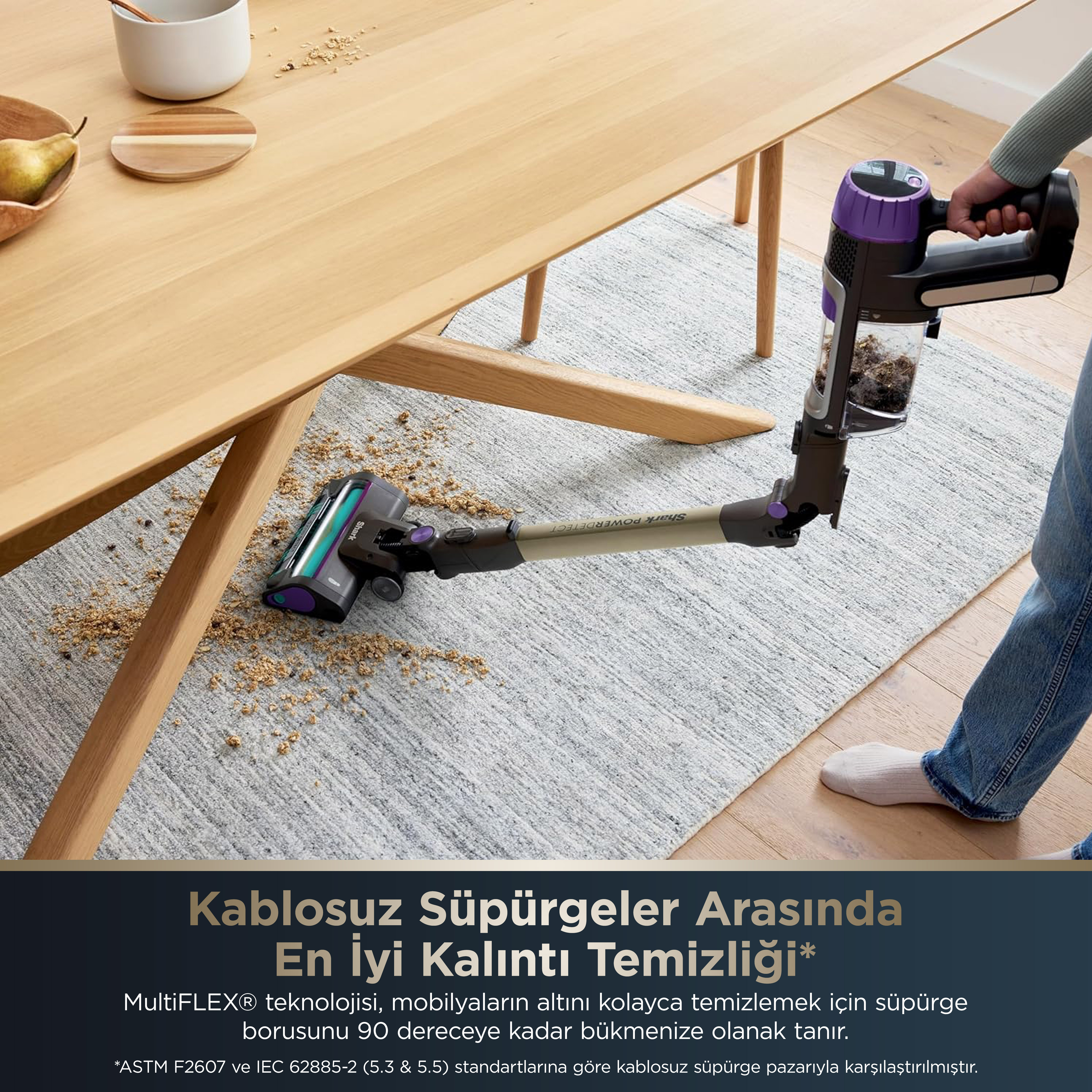 Bir kişi halıda kablosuz bir elektrikli süpürgeyle süpürme yapıyor.