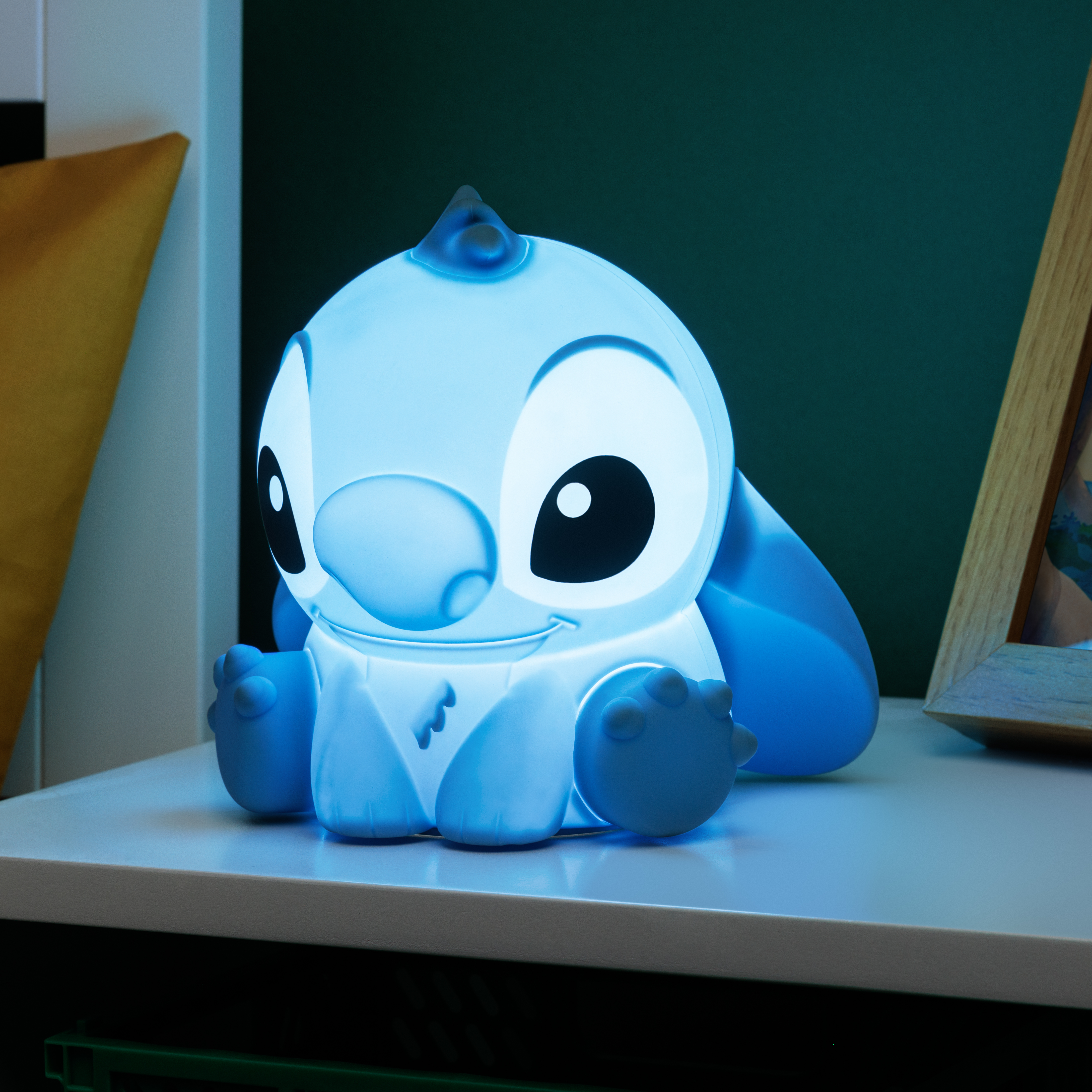 Blau leuchtende Stitch-Lampe auf weißer Oberfläche mit grünem Wandhintergrund.