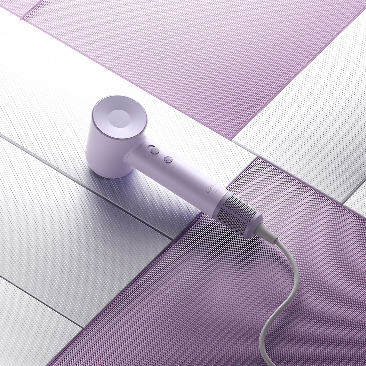 Un asciugacapelli bianco e viola poggia su una superficie con sfondo a motivi. Un cavo si estende dal dispositivo.