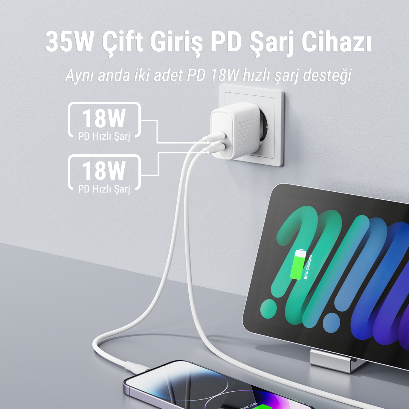 Duvar prizine takılı iki USB-C kablosu olan beyaz bir şarj cihazı. Bir telefon ve tablet şarj oluyor.