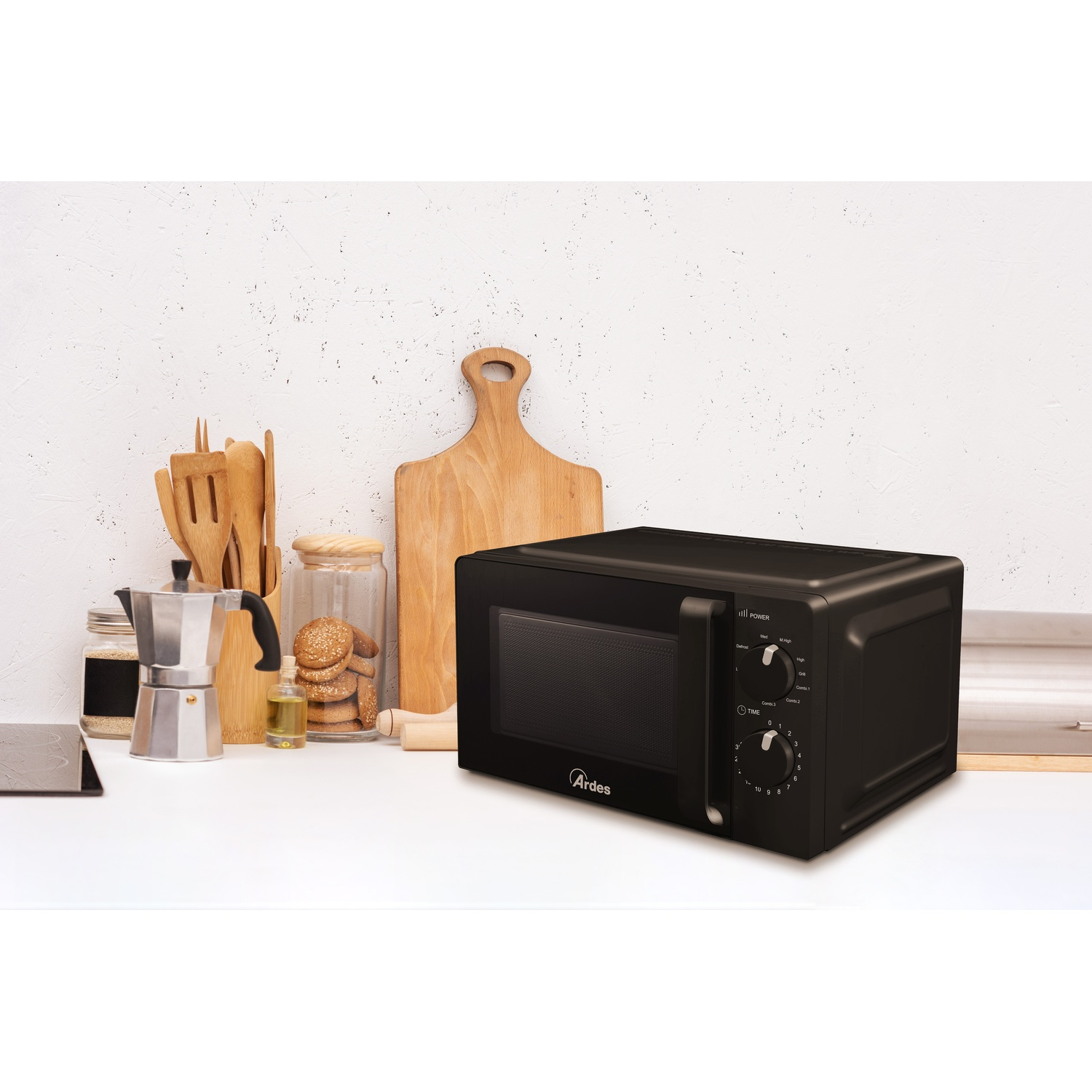 Microonde Ardes nero in cucina. Tagliere e utensili in legno sullo sfondo.