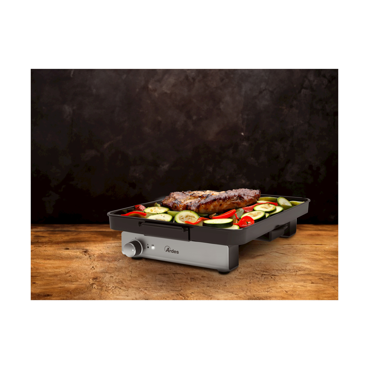 Griglia elettrica con bistecca e verdure cotte. Tavolo di legno e sfondo scuro.