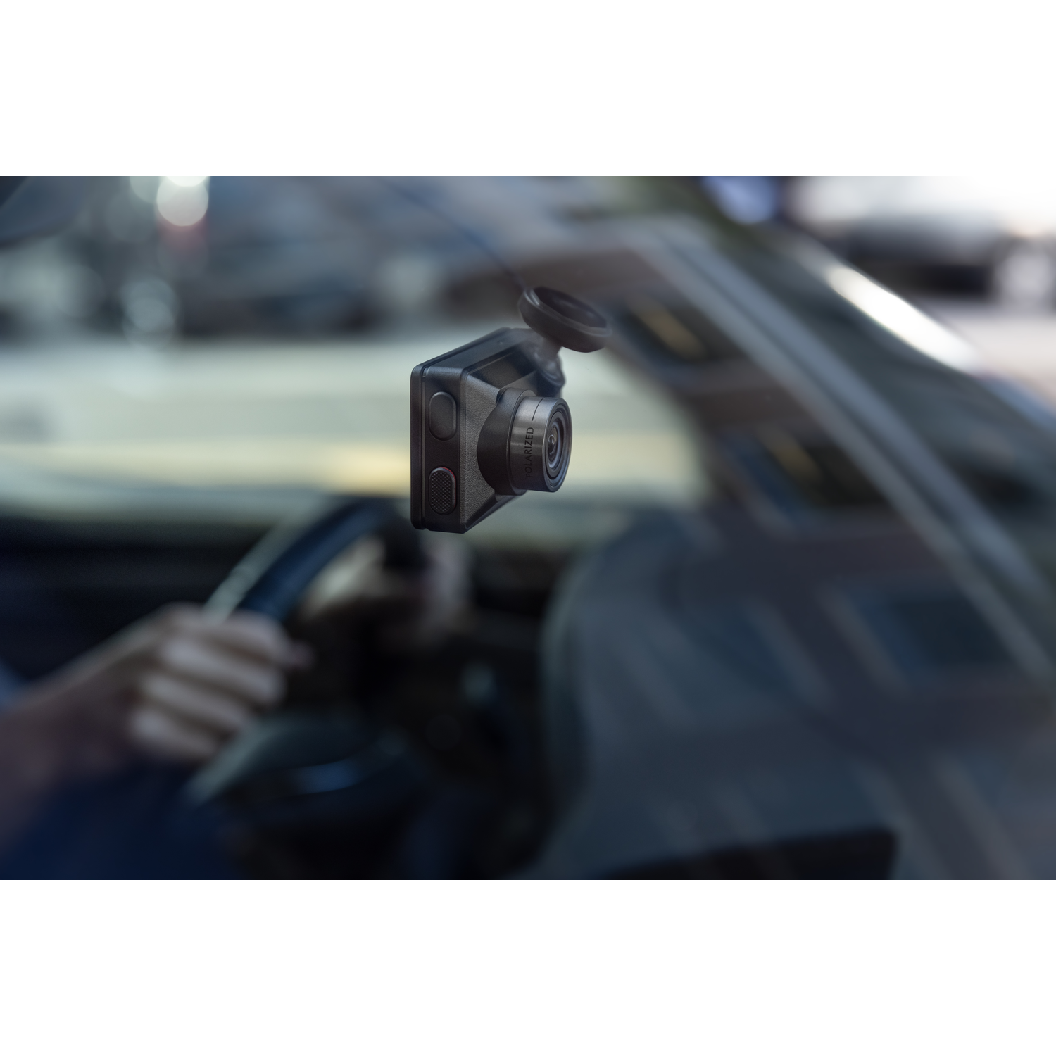 Een zwarte dashcam gemonteerd op een autoruit, met een vage achtergrond van een weg.