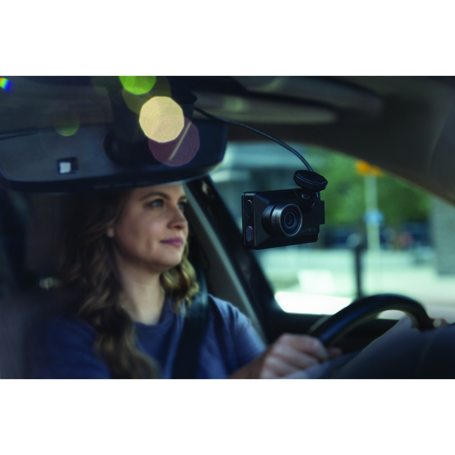 Een vrouw die een auto bestuurt, met een dashcam op de voorruit gemonteerd.