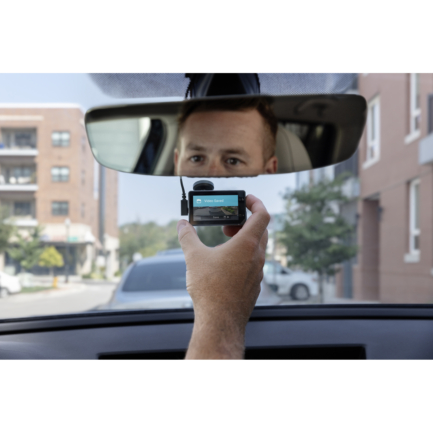 Persoon die een dashcam vasthoudt, met een opgeslagen videoboodschap, auto-interieur.