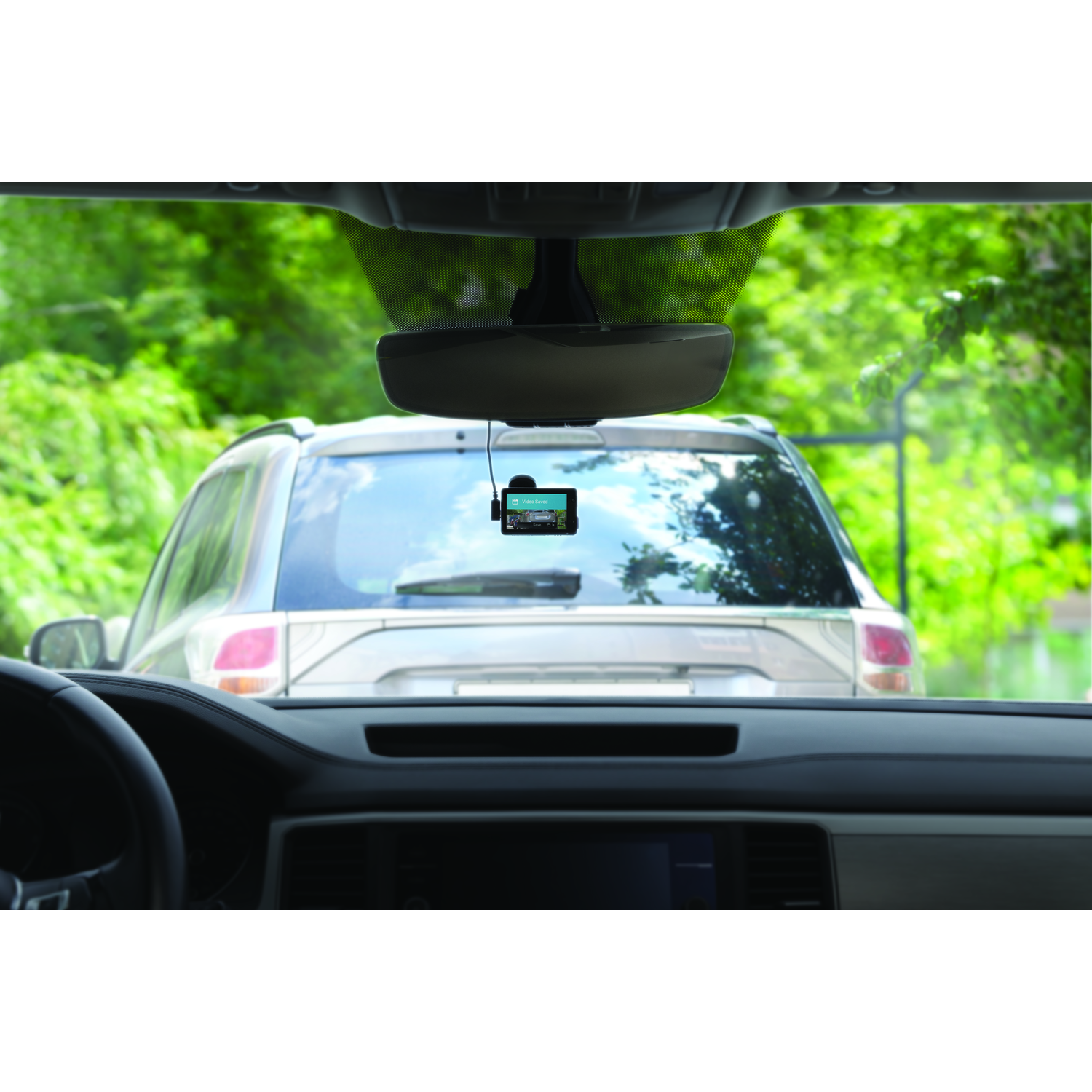 Interieur van de auto. Dashcam op voorruit, achteruitkijkspiegel, bomen zichtbaar.