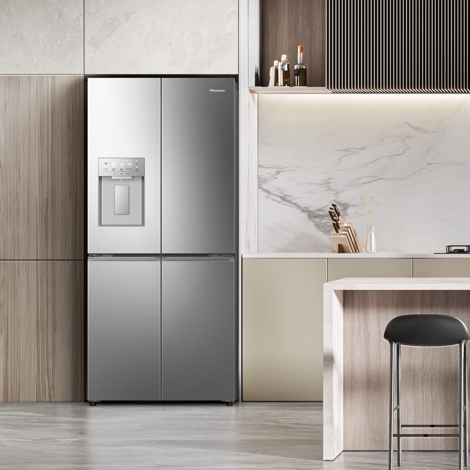Un moderno refrigerador plateado de cuatro puertas, dispensador, en un interior de cocina con taburete y mostrador.