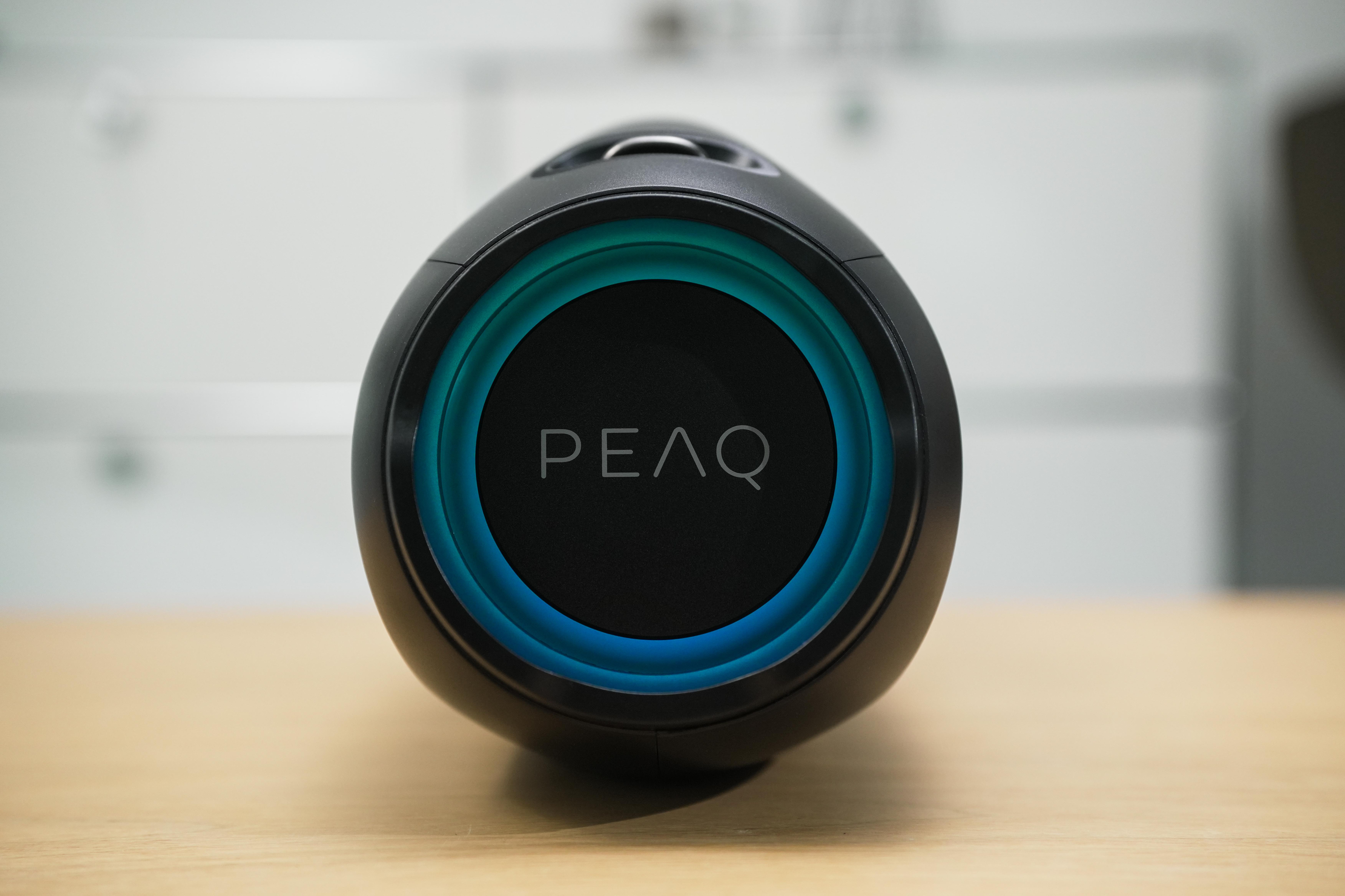 Schwarzer Lautsprecher mit blau leuchtendem Ring um das PEAQ Logo.