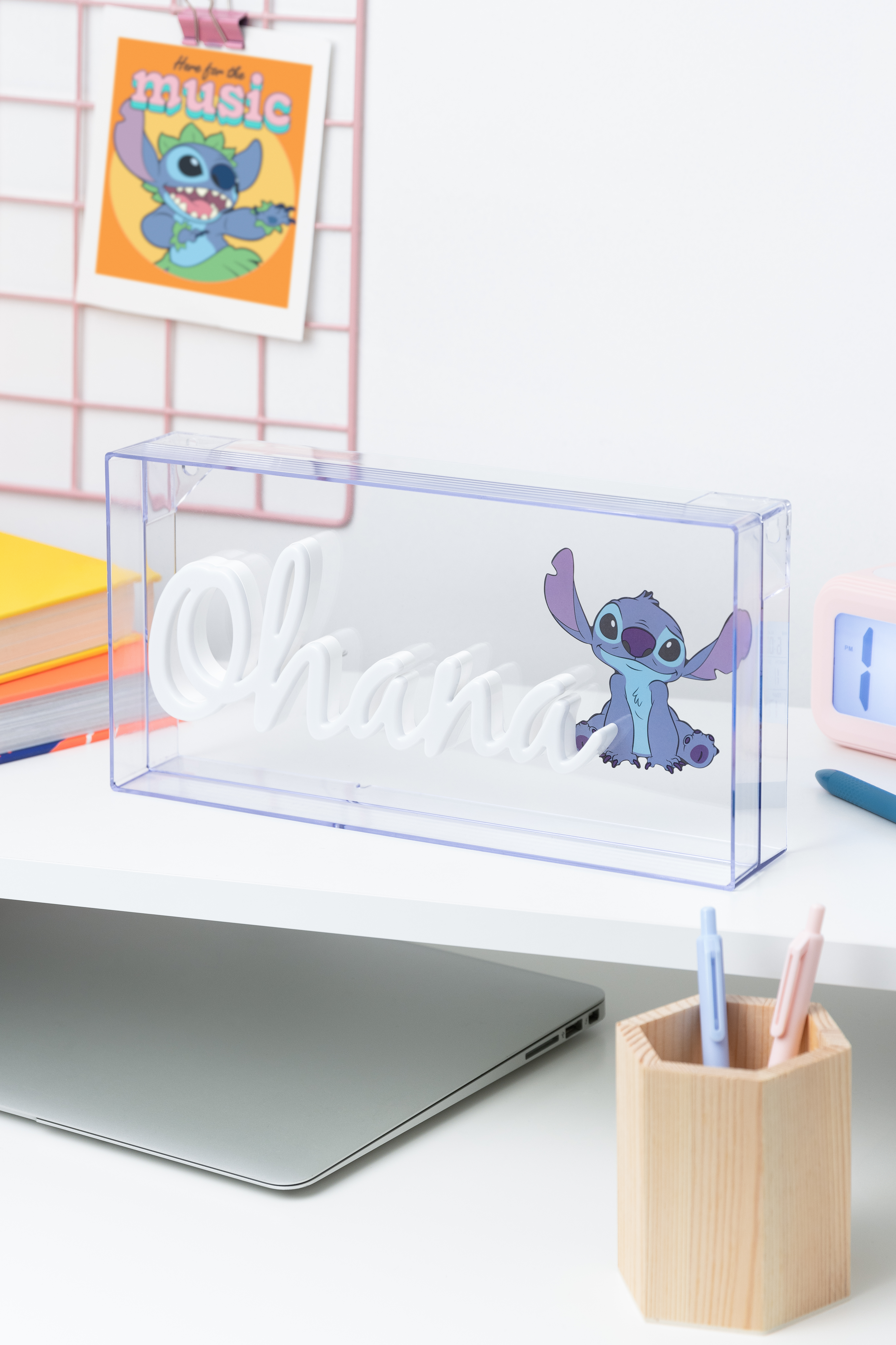 Ein Schreibtisch mit Laptop, 'Ohana'-Schild in einer Box und einem Stitch-Aufkleber.