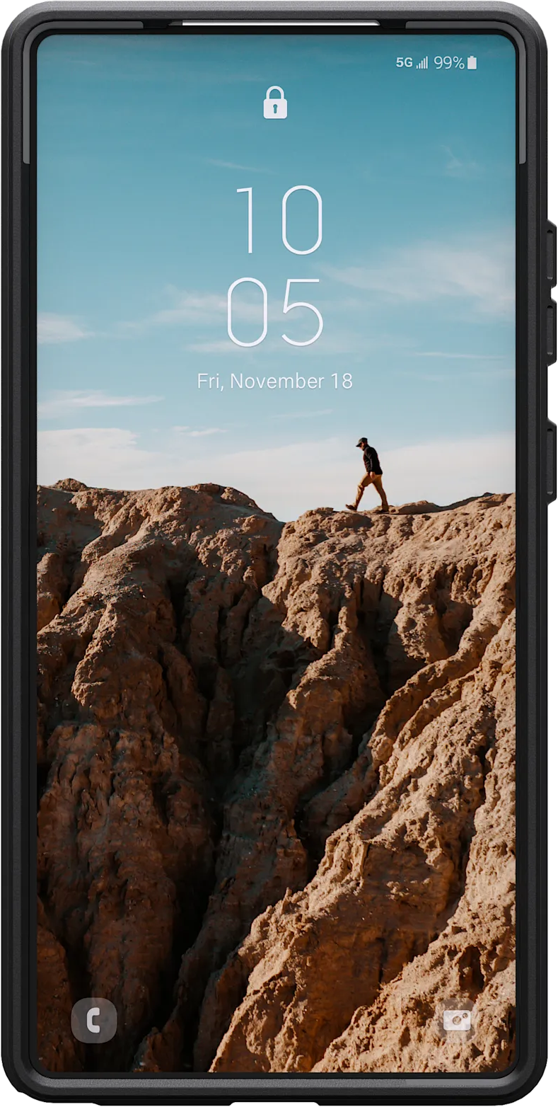 L'écran du téléphone affiche une personne marchant sur une crête rocheuse. La date et l'heure sont affichées. Le ciel est bleu.