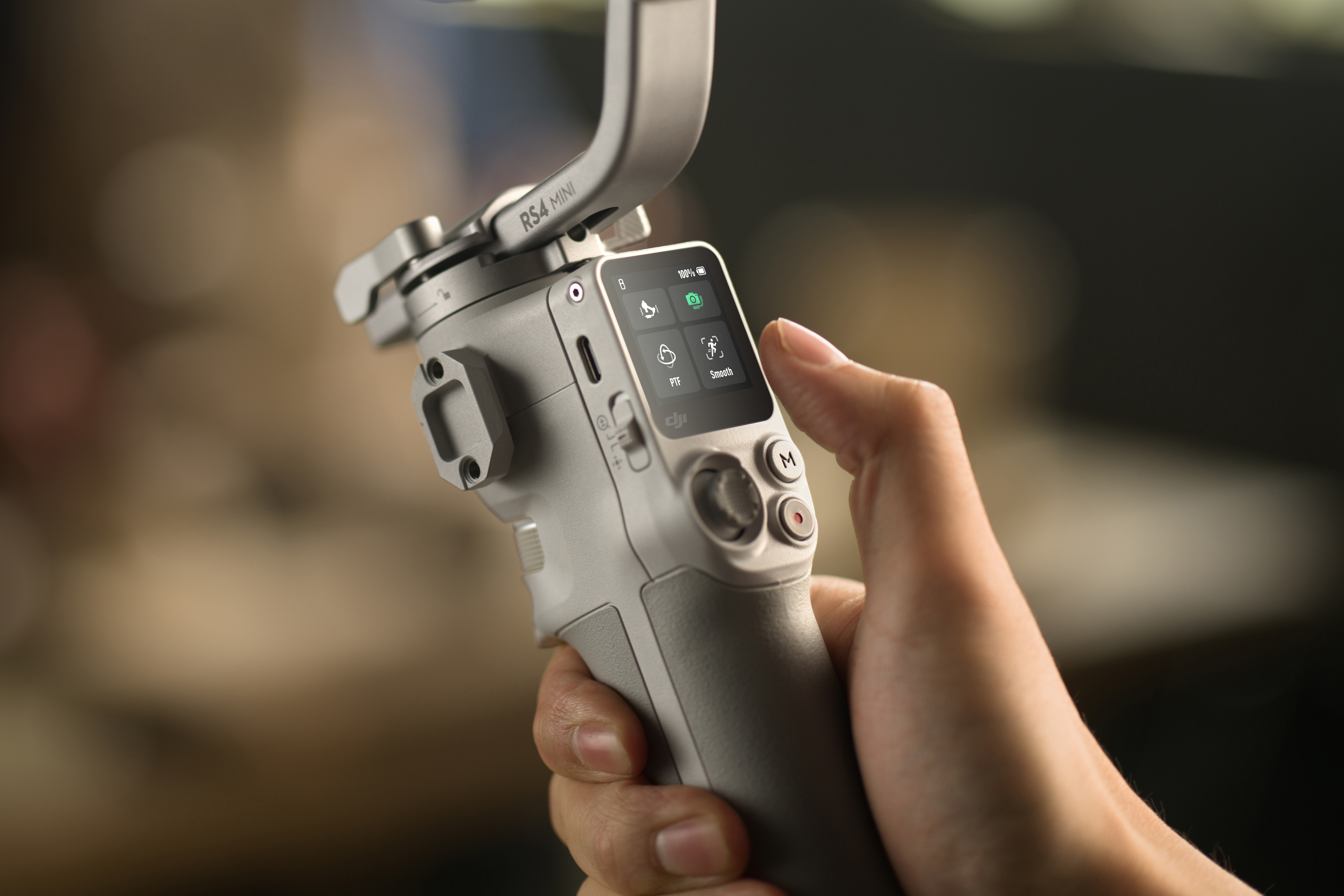 Eine Hand drückt auf den Bildschirm eines DJI-Stabilisators. Es hat Knöpfe und einen Bildschirm.