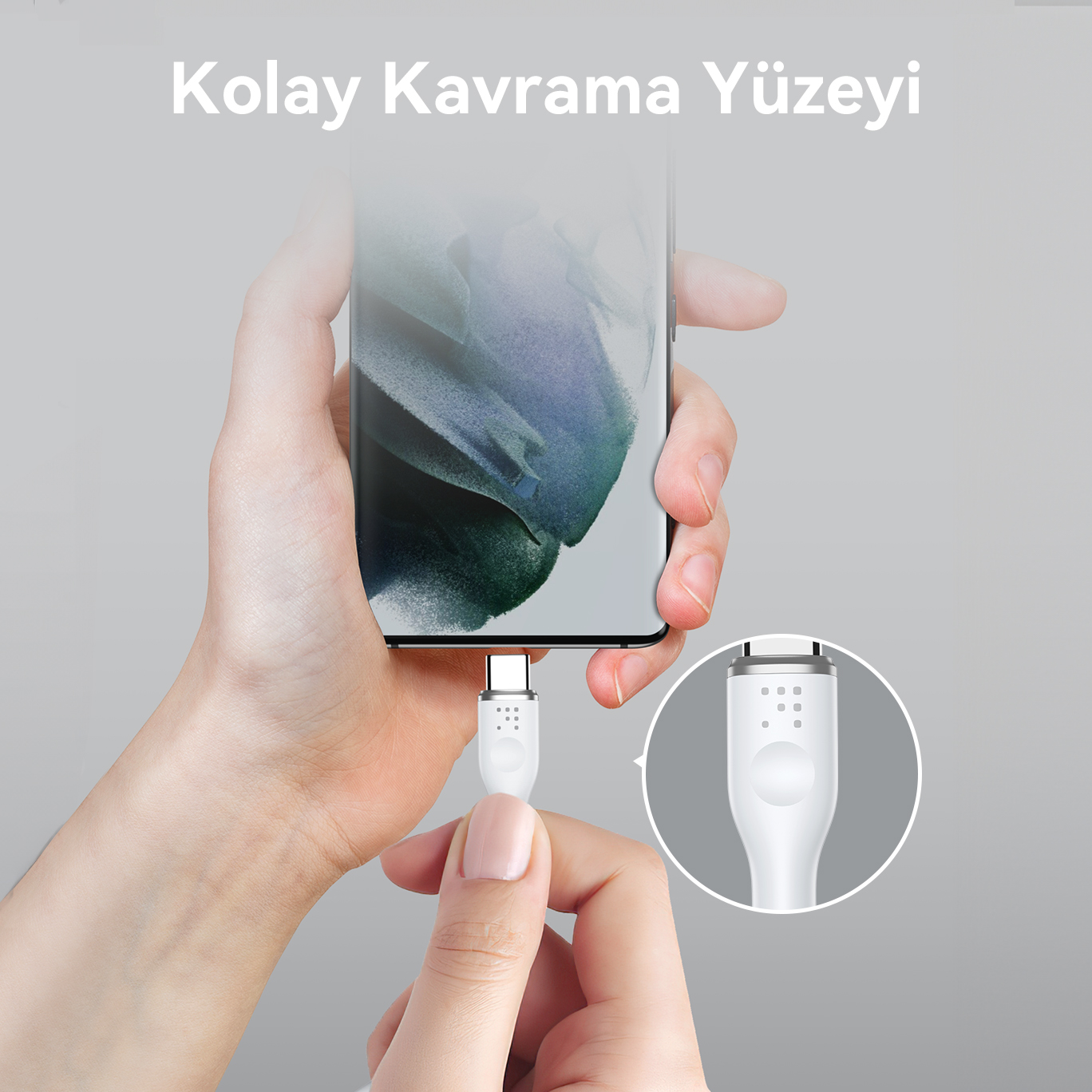 El, siyah bir telefona bağlı beyaz bir USB-C kablosu tutuyor.