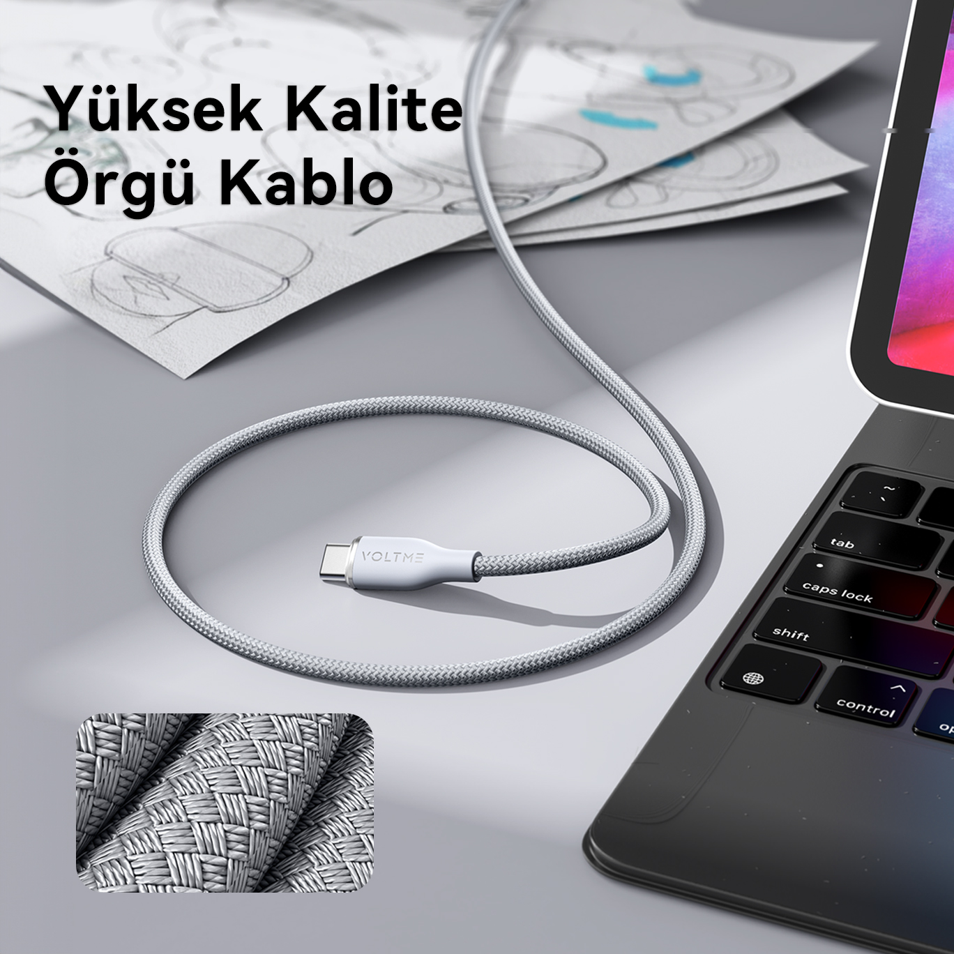 Gri örgülü bir USB-C kablosu bir dizüstü bilgisayar ve tablete bağlı. Metin yerleşimi.