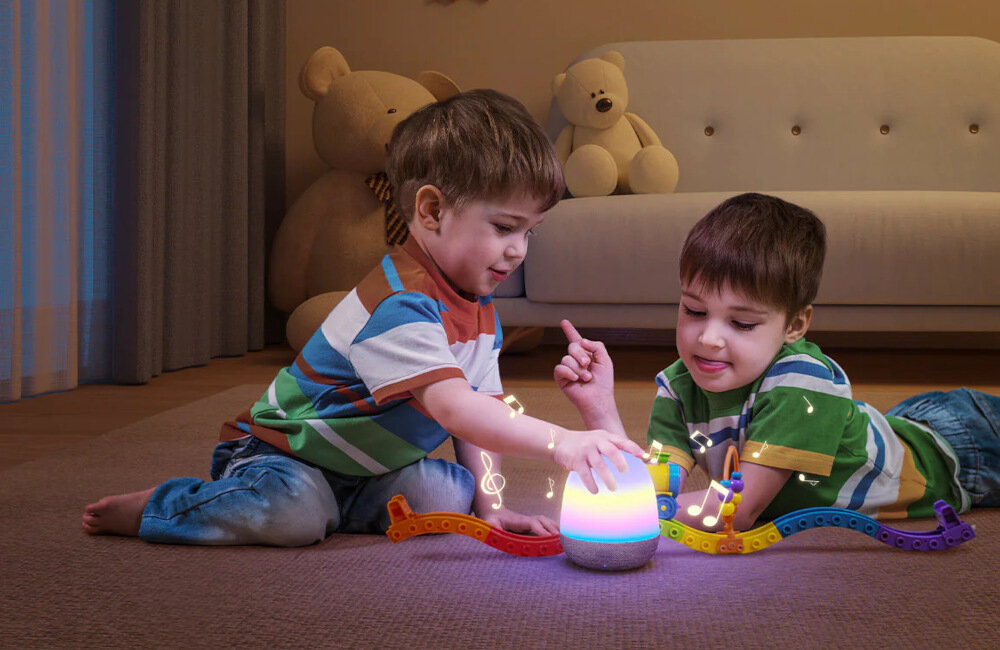 Dwoje dzieci bawiących się podświetlaną zabawką. W tle sofa i pluszowe misie.