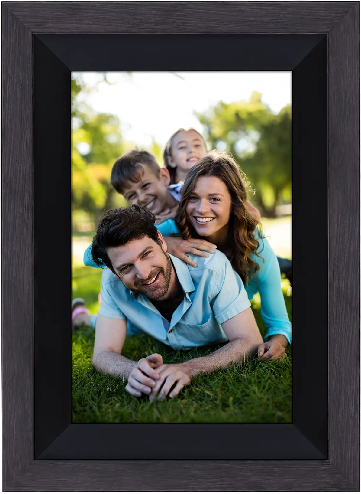 Portrait de famille dans un cadre. Un homme est allongé, des enfants derrière lui, et une femme. Tous souriants dans l'herbe.