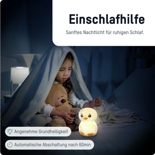 Ein Kind unter einer Decke mit einem Teddybären, ein Enten-Nachtlicht steht auf dem Boden.