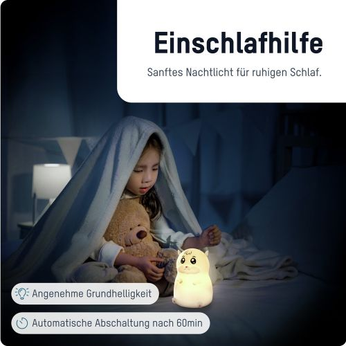 Ein Mädchen unter einer Decke mit einem Teddybär und einem Nachtlicht in einem dunklen Raum.