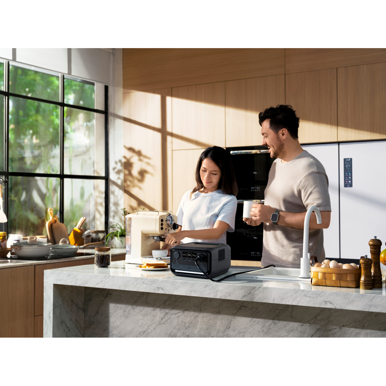 Couple in a kitchen. Woman makes coffee, man watches. Power station on counter.