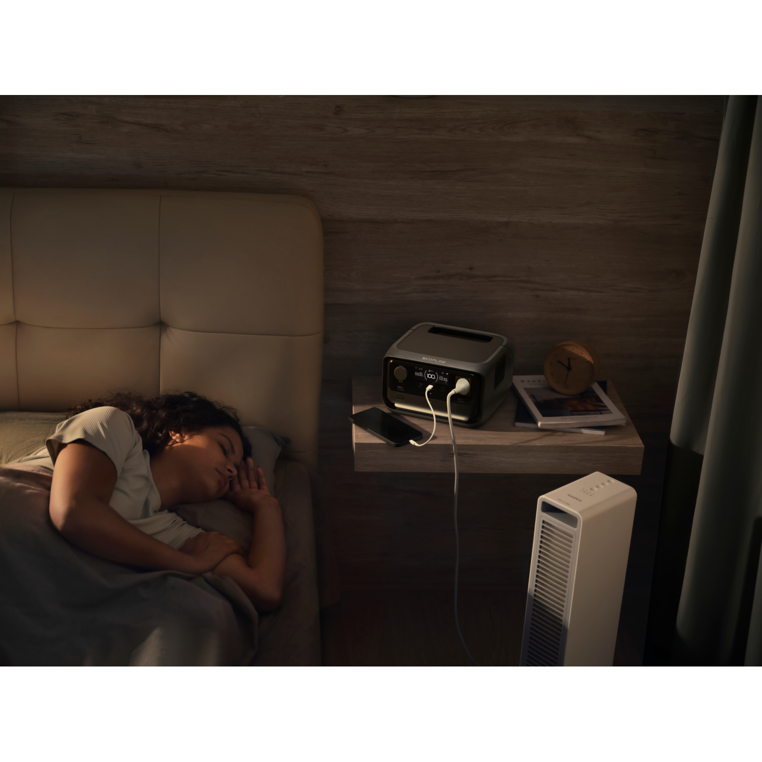 A woman sleeps in bed with a power bank and a lamp on the nightstand. The room is dark.