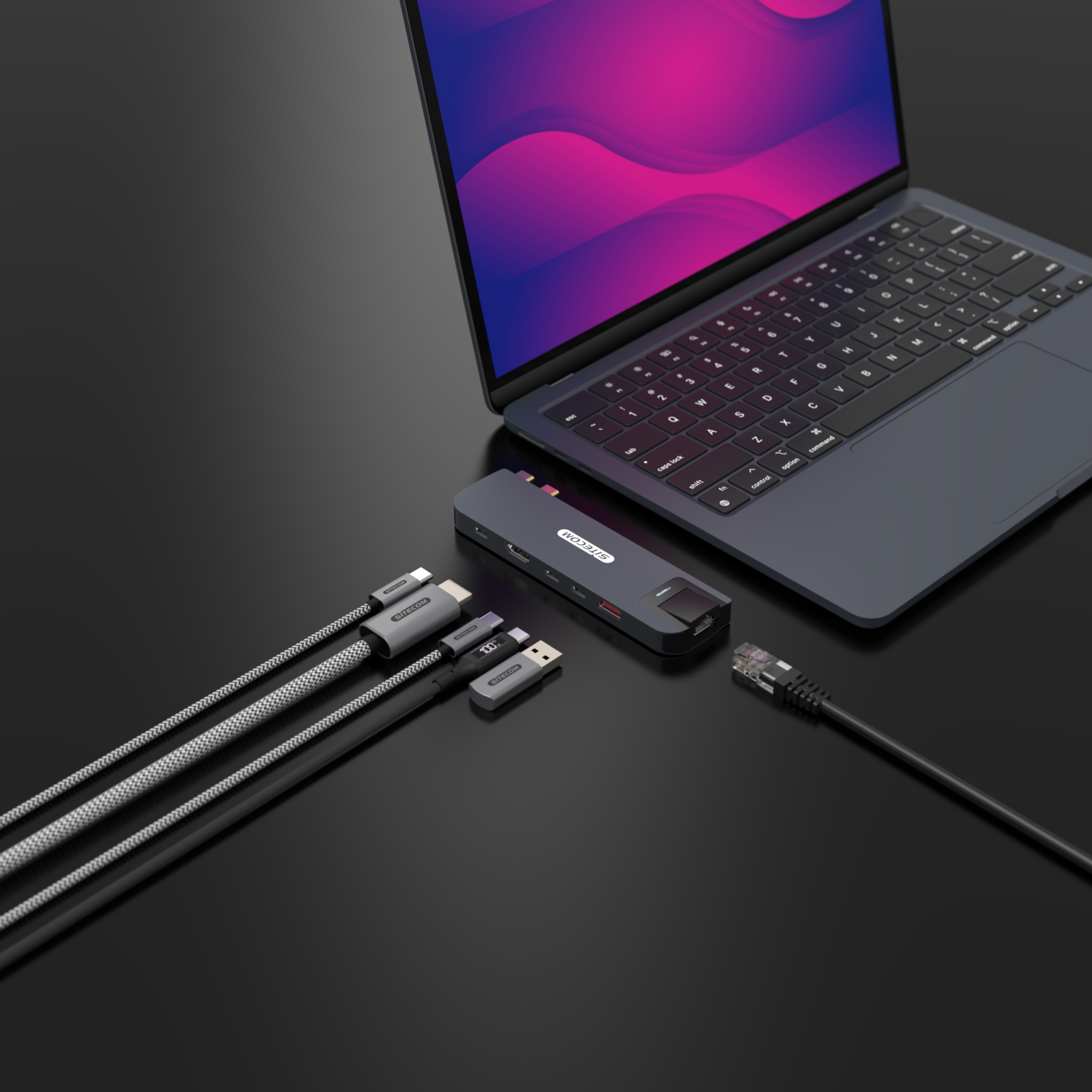 Laptop, hub, and cables on a dark surface.