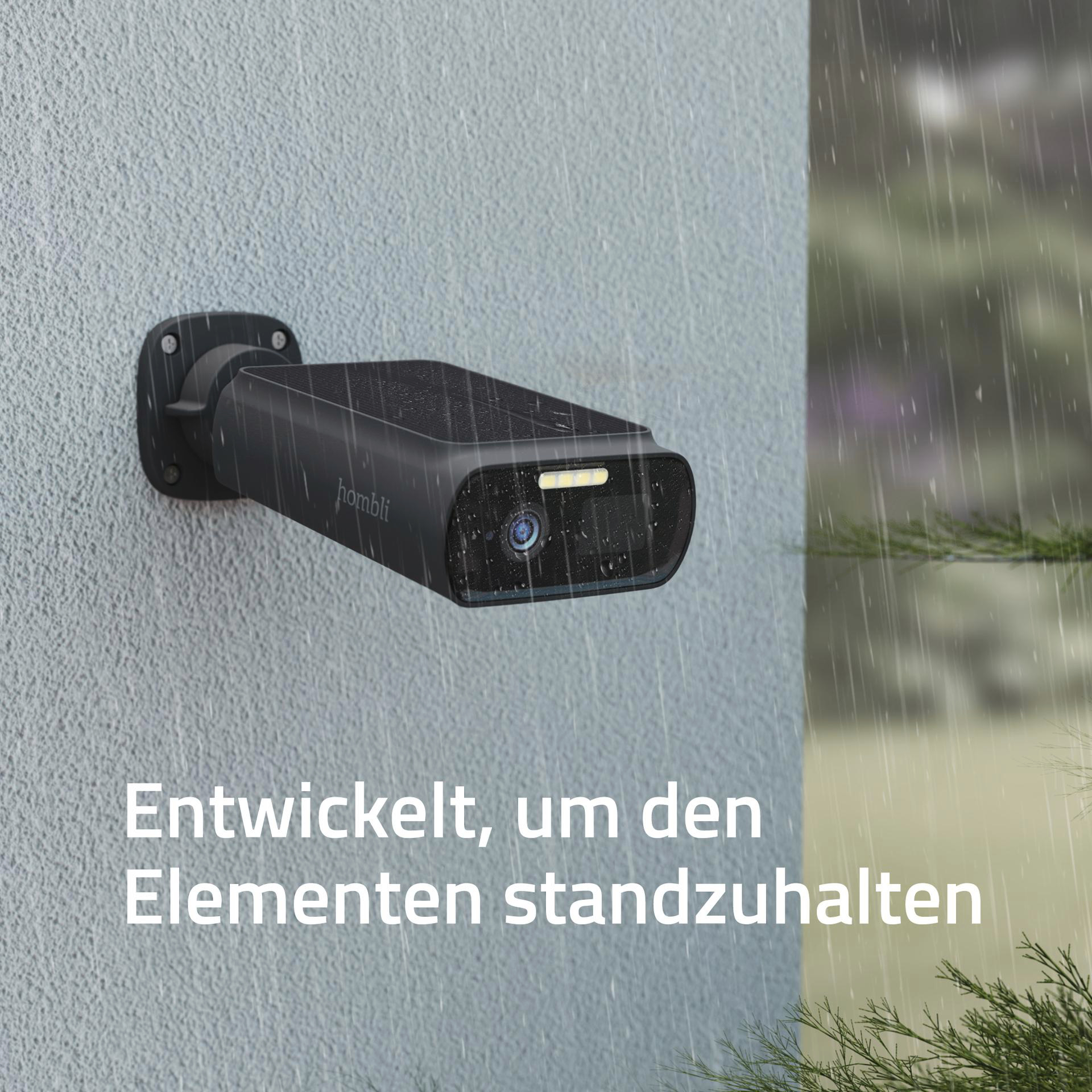Eine schwarze Überwachungskamera an einer Wand mit fallendem Regen.