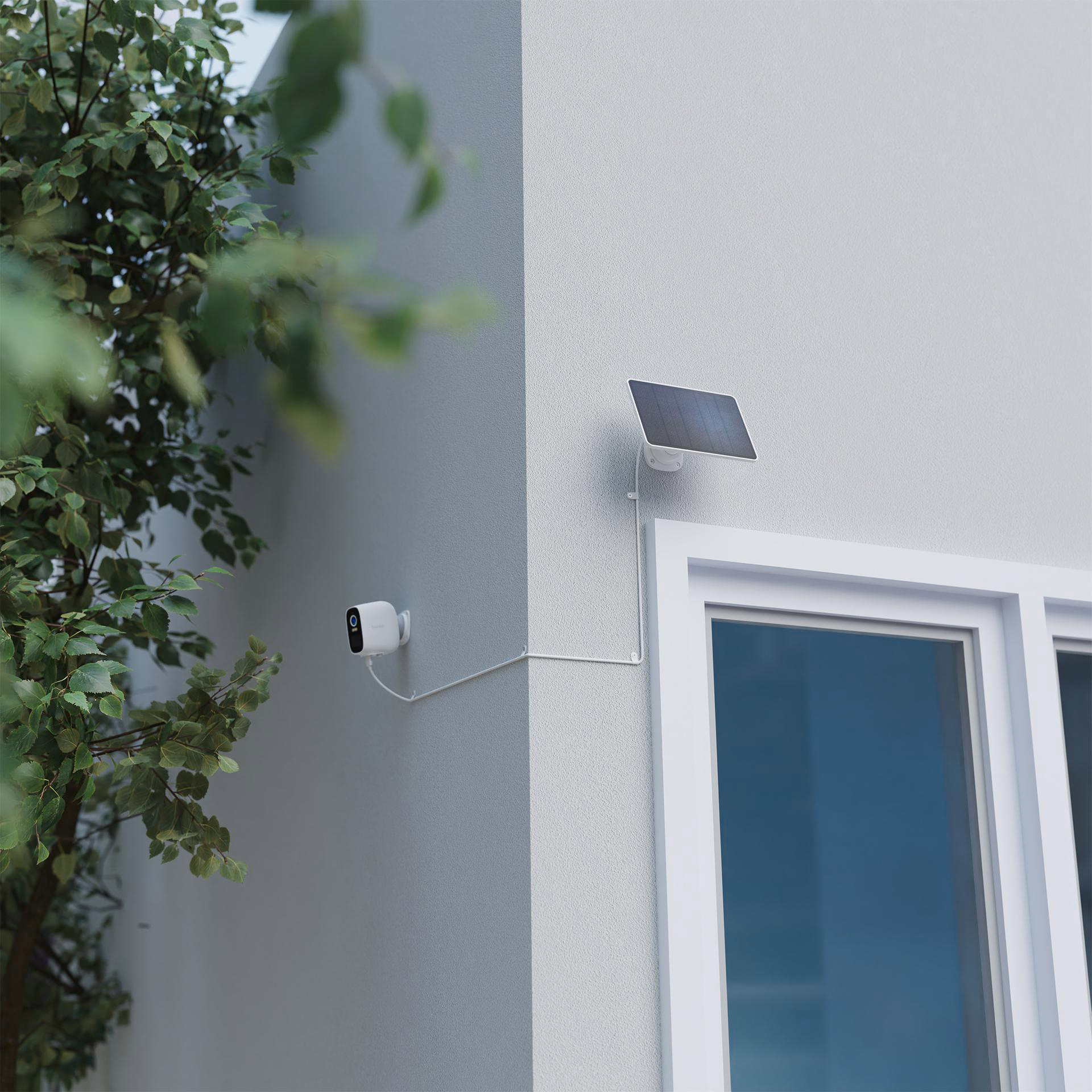 Eine weiße Überwachungskamera, ein Solarpanel und ein weißes Fenster. Die Kamera ist an einer Wand montiert.