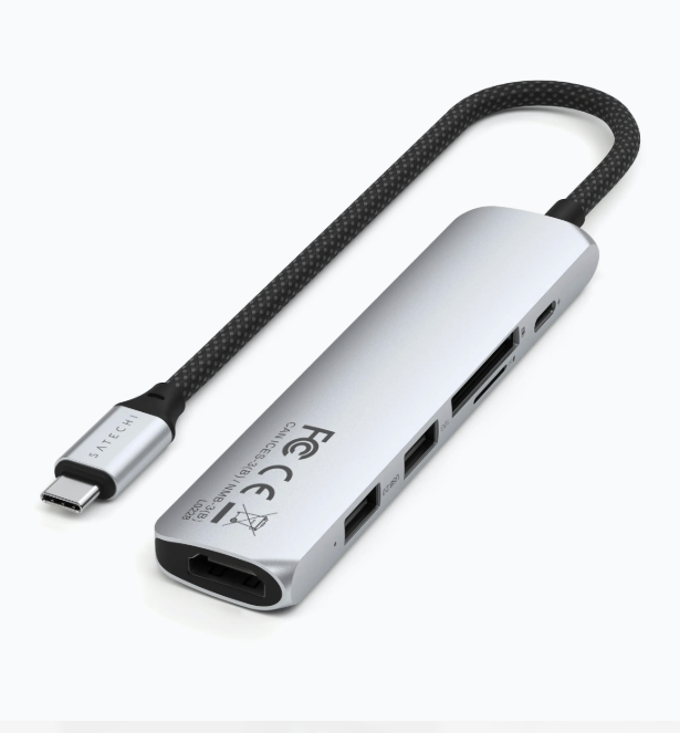 Ein silberner USB-C-Hub mit mehreren Anschlüssen und einem schwarzen Kabel. Es ist auf weißem Hintergrund.