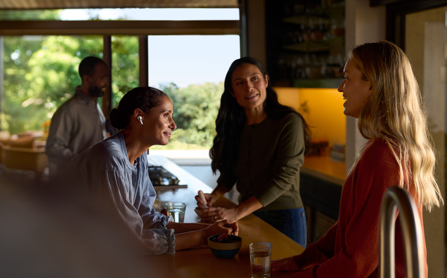 People talking near a table. One is wearing AirPods.