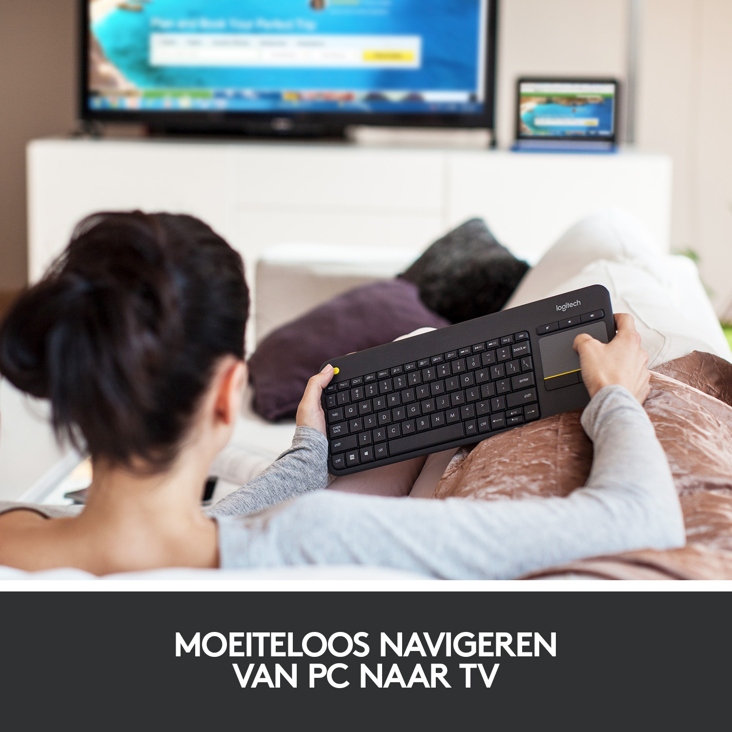 Woman uses a black keyboard with touchpad. TV is in the background.