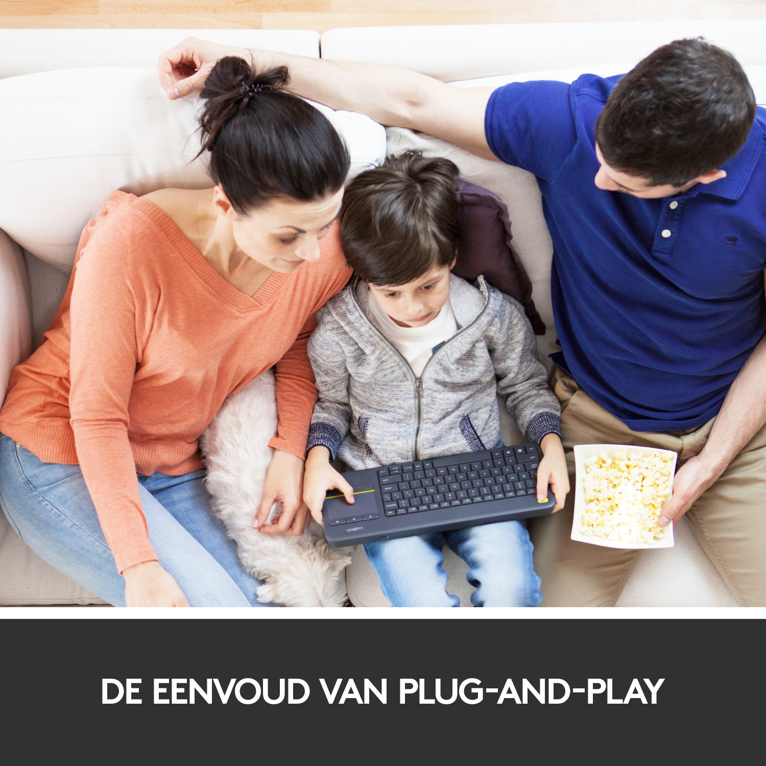 Family on a sofa, using a keyboard while eating popcorn.