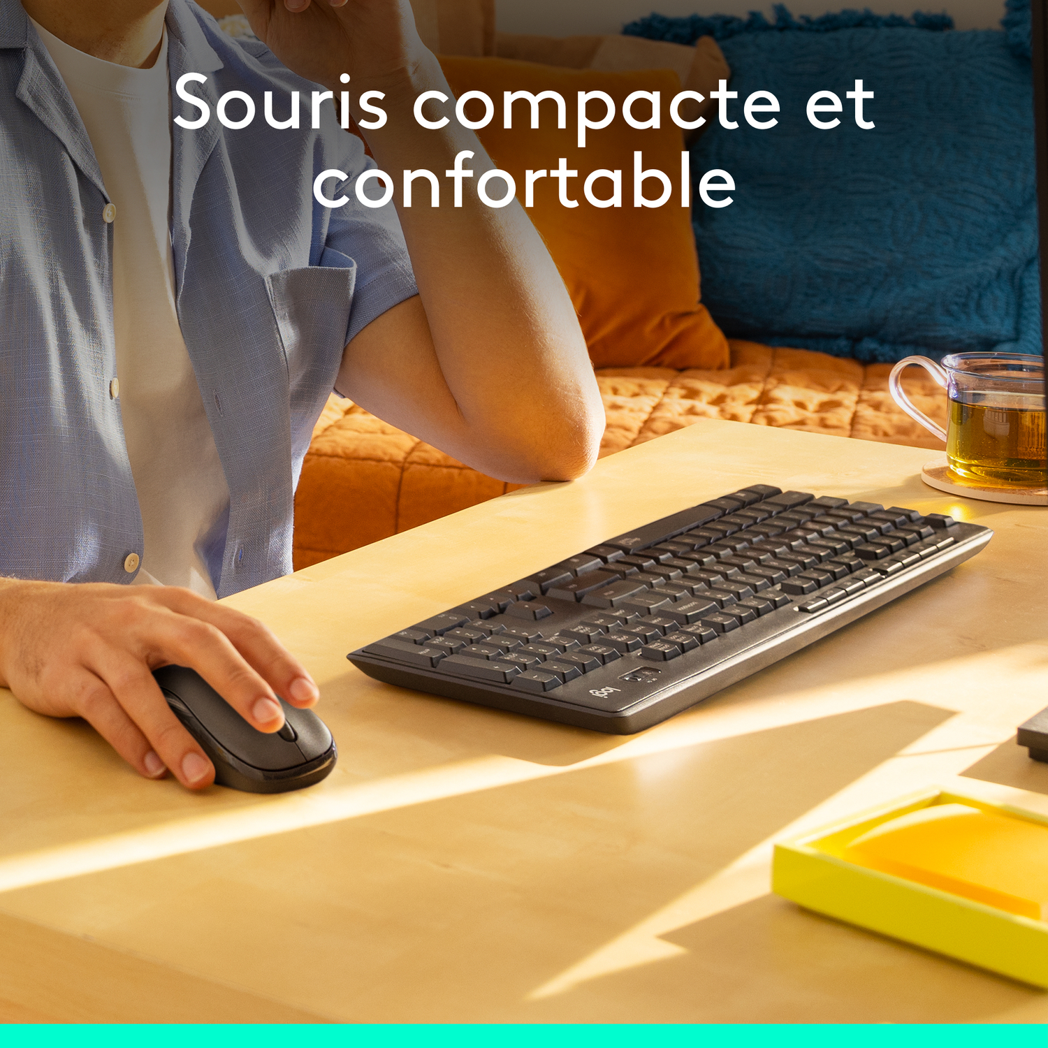 Un homme utilise une souris et un clavier sur une table en bois.