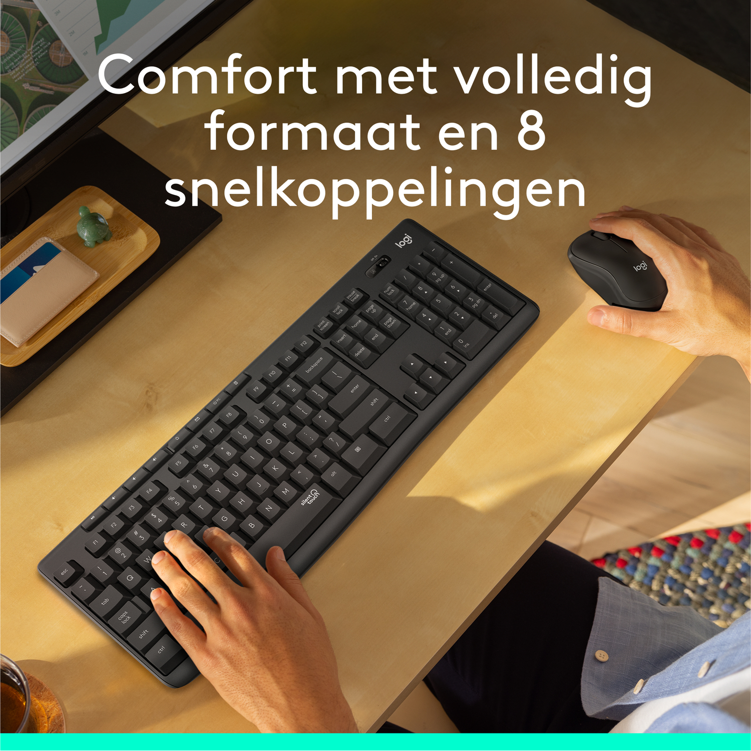 Man uses keyboard and mouse on a wooden desk. 