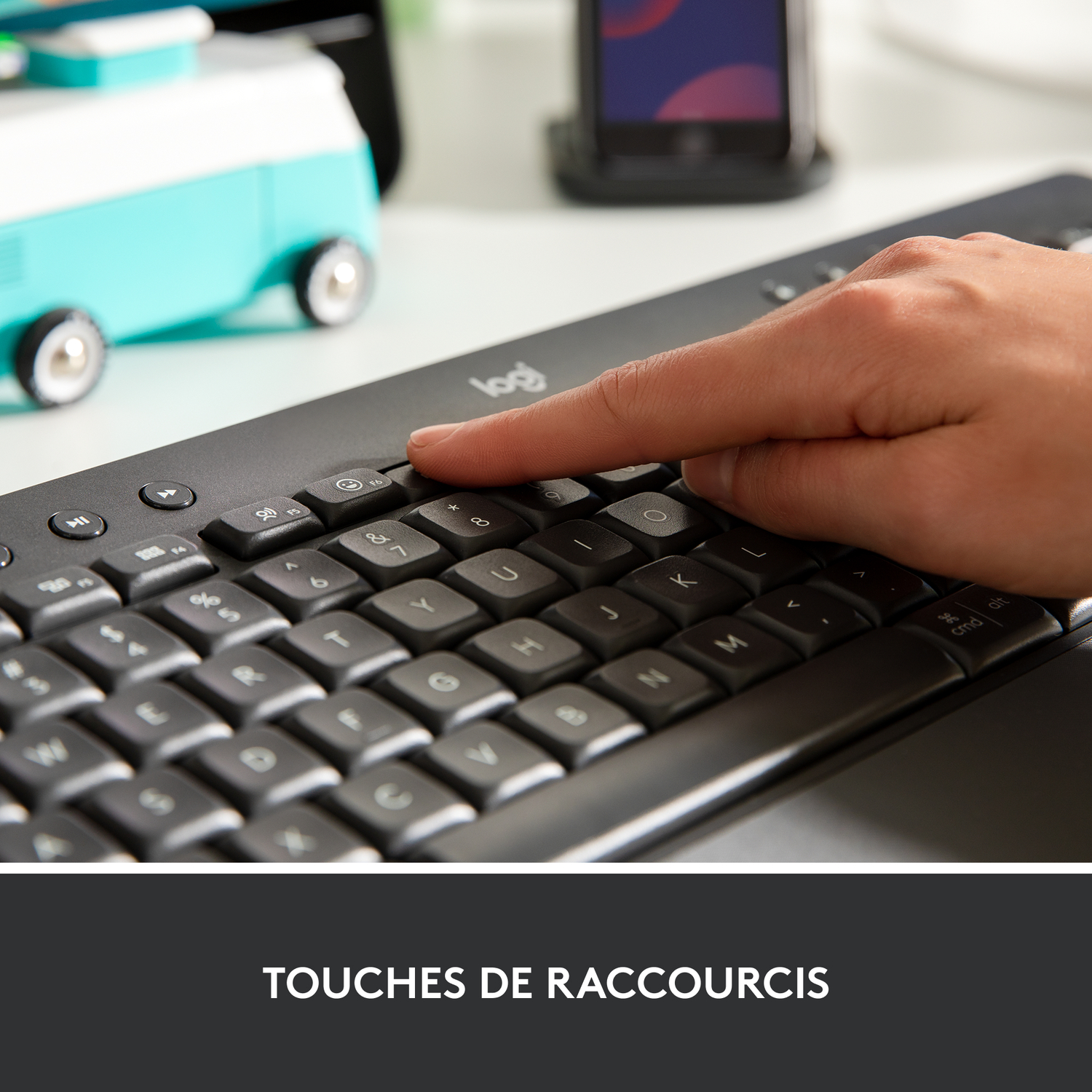 Doigt appuyant sur une touche d'un clavier noir. Le clavier est sur une surface blanche.