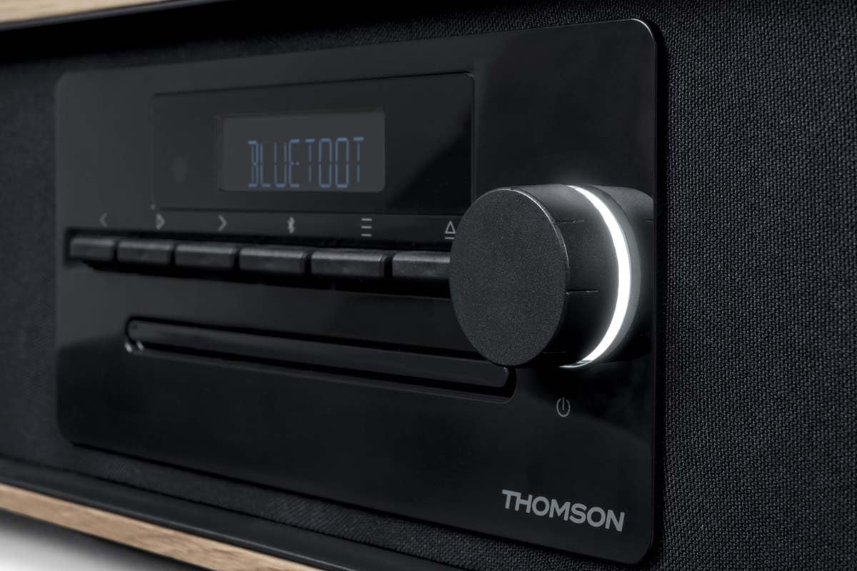 Primer plano de un sistema de audio negro con una perilla y una pantalla. La pantalla dice 'BLUETOOT'.