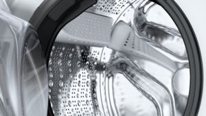 Nahaufnahme einer Waschmaschinentrommel, die einen Edelstahlinnenraum mit Wassertropfen zeigt.