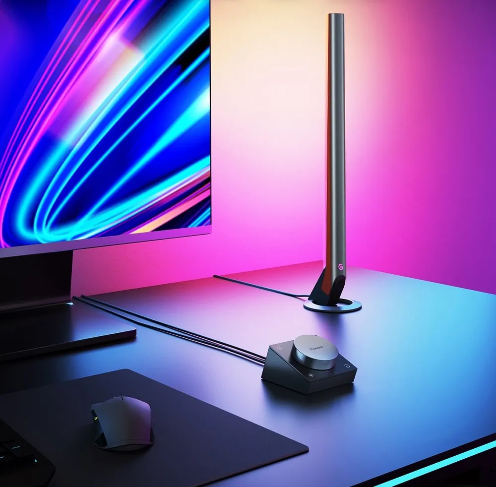 Konfiguracja biurka z monitorem, soundbarem i myszą, z efektem neonowego światła.