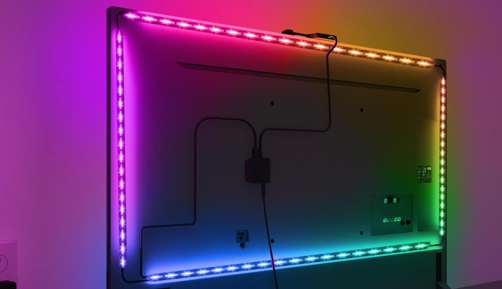 Telewizor z kolorowymi paskami LED na tylnej ścianie.