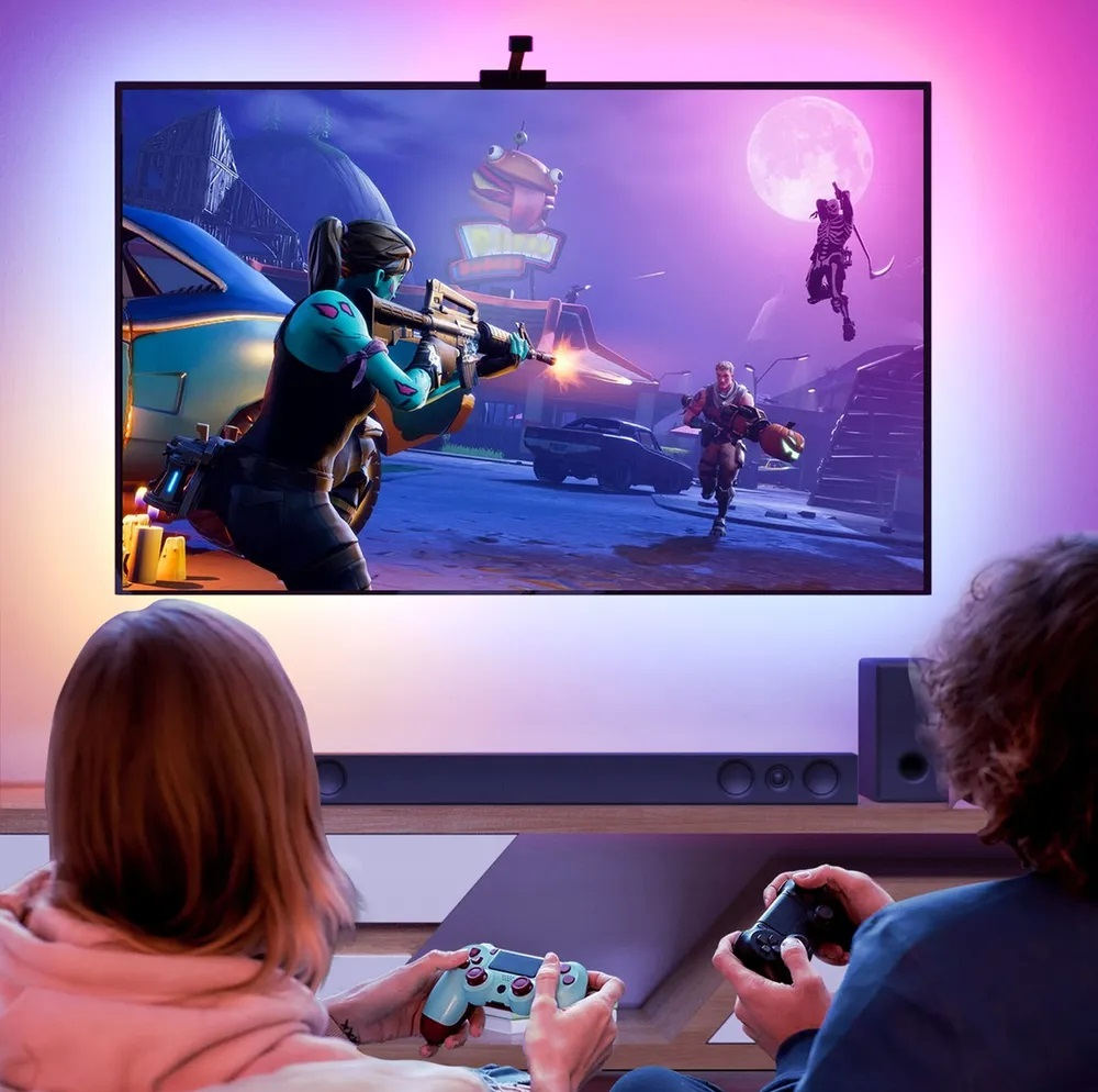 Ludzie grają w grę na telewizorze. Telewizor wyświetla scenę z gry z oświetleniem ambient.