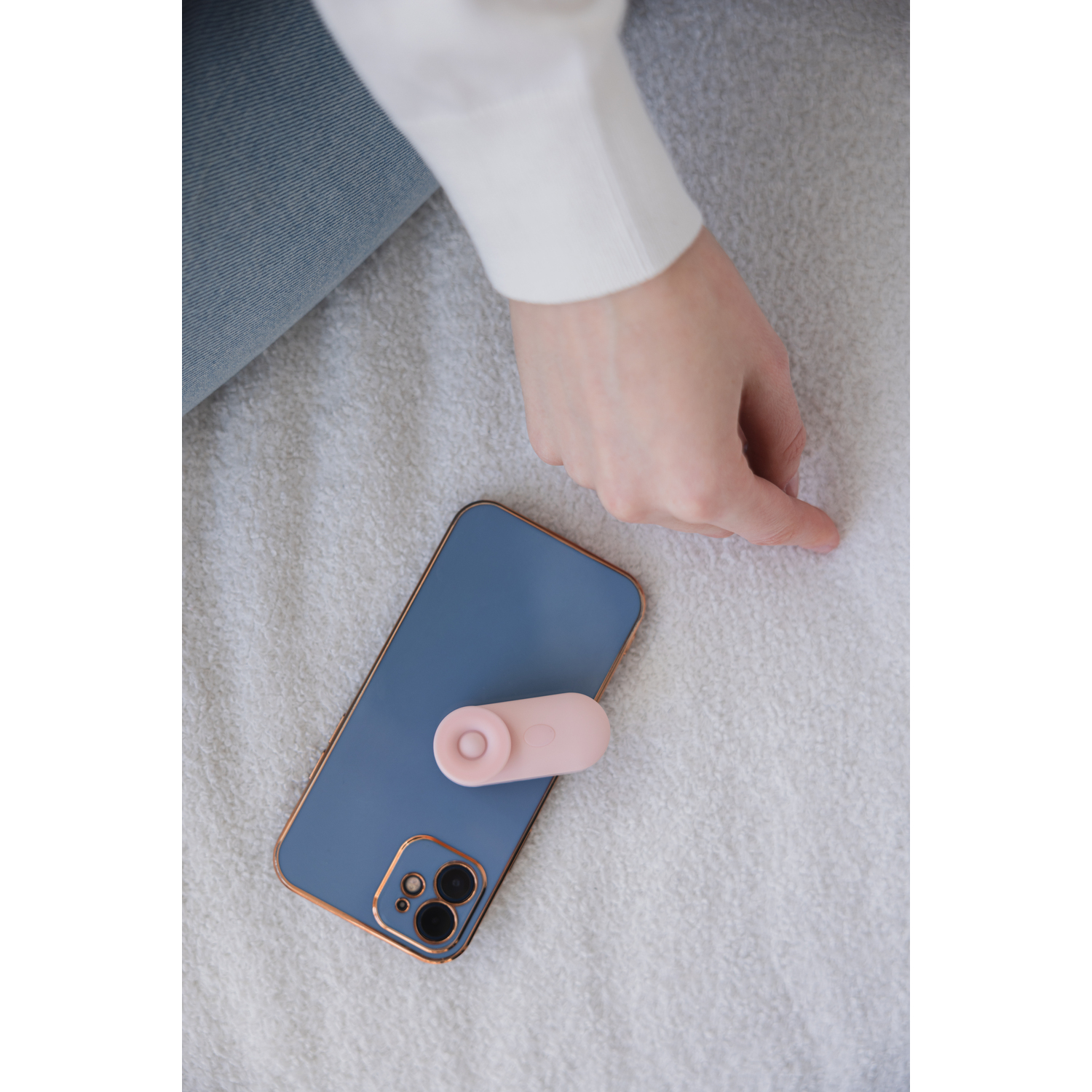 Hand near a blue phone with a pink sex toy attached.