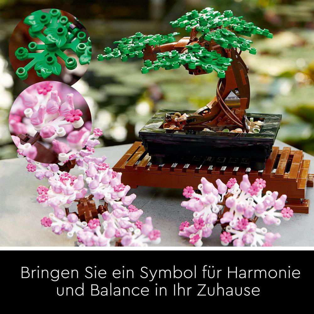 Ein LEGO Bonsai-Baum mit rosa Blüten, auf einem Holzständer, mit verschwommenem Hintergrund.