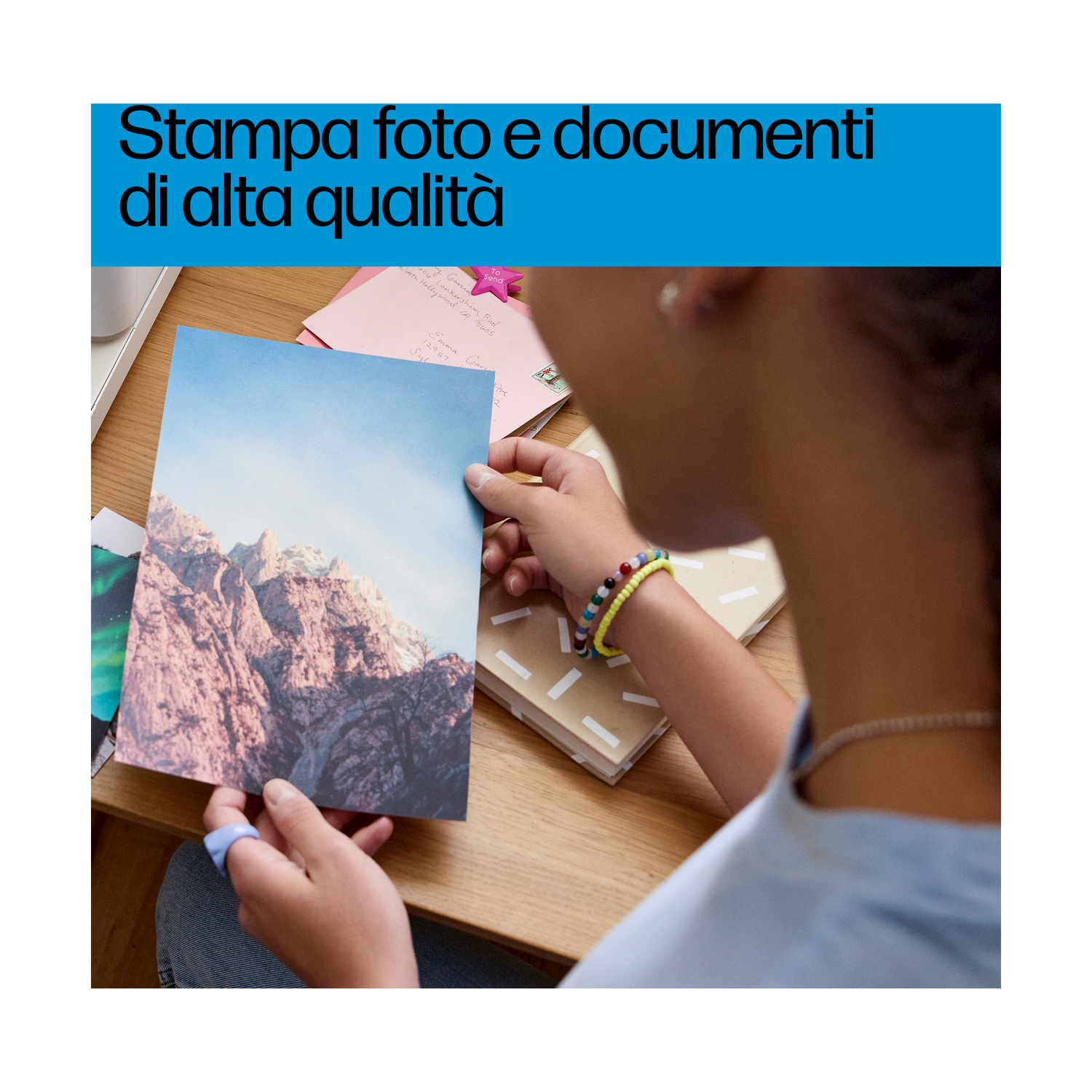 Persona che tiene una foto stampata di montagne, con testo sopra.