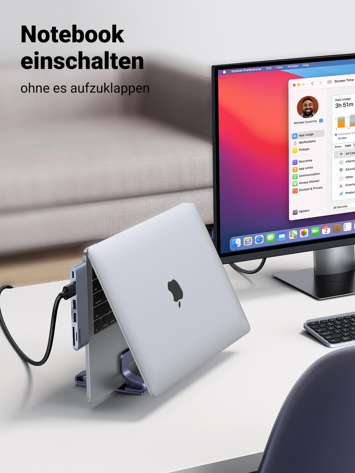 Ein Laptop auf einem Ständer, verbunden mit einem Monitor. Der Laptop ist leicht geöffnet, Bildschirm sichtbar. Schreibtisch ordentlich.